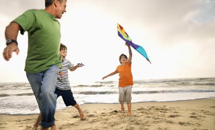 Father and children flying a kite on the beach