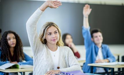 A student in a classroom raising her hand